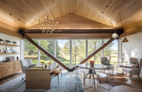 Warm, modern interior with wood-paneled ceiling, large windows, and sleek furnishings.