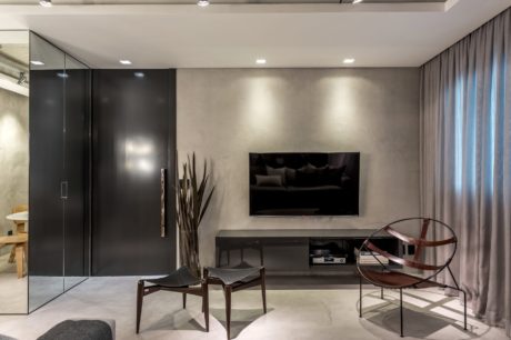 Minimalist living room with dark furniture, large TV, and contemporary lighting.