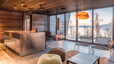 A modern, rustic cabin interior with a large window overlooking a scenic landscape.