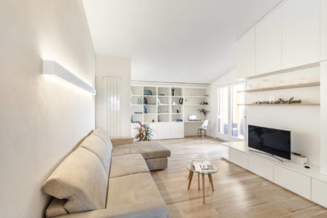 Spacious, minimalist living room with built-in shelves, wood floors, and large windows.