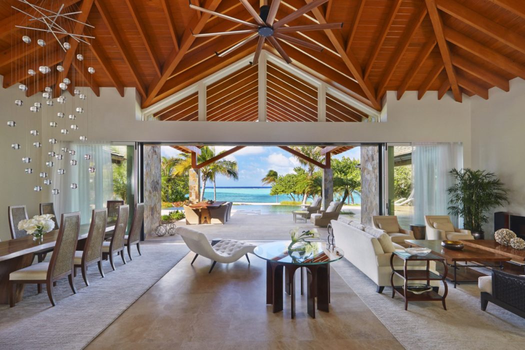 Luxurious interior with vaulted wooden ceiling, large windows overlooking beach.
