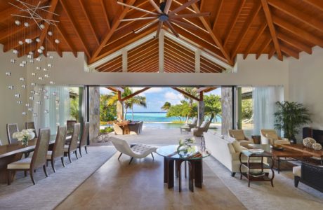 Luxurious interior with vaulted wooden ceiling, large windows overlooking beach.