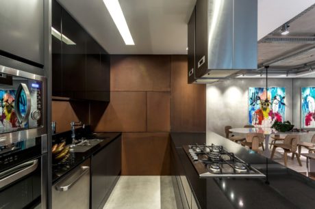 Modern kitchen design featuring sleek black cabinets, integrated appliances, and vibrant abstract artworks.