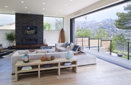 Spacious living room with large windows, sleek furniture, and a rustic wooden coffee table.
