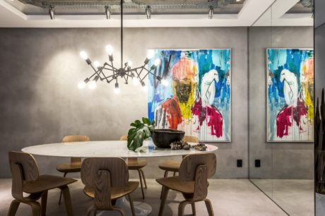 Sleek, modern dining space with abstract artwork, chandelier, and natural wood furnishings.