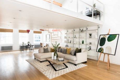 Bright, open-concept living room with neutral furnishings, wood accents, and shelving unit.