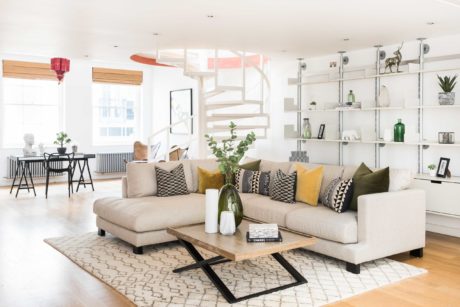 Bright, open-concept living space with modern furnishings, shelving, and plants.