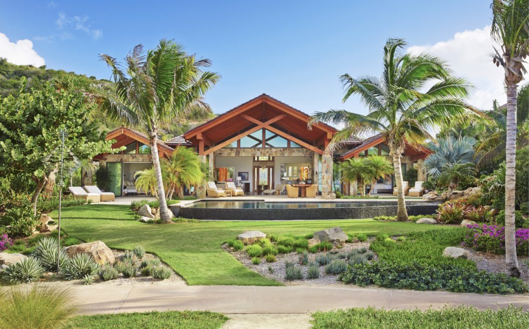 Stunning tropical villa with lush gardens, thatched roof, and expansive outdoor living area.