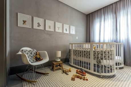 Neutral-toned modern nursery with circular crib, rocking chair, and framed artwork on wall.