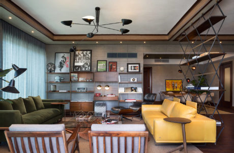 Stylish and eclectic living room with modern lighting, shelving, and industrial-inspired decor.