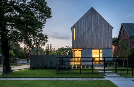 Modern wooden structure with sleek black metal railing and illuminated interior.