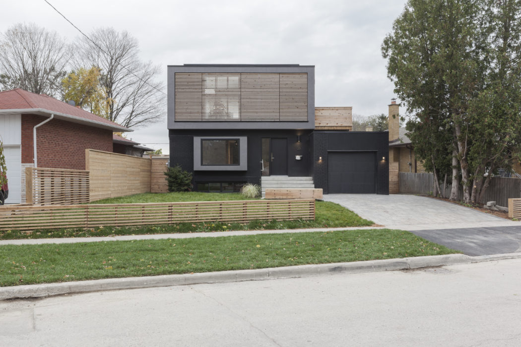 Modern two-story home with sleek black facade, minimalist design, and landscaped yard.