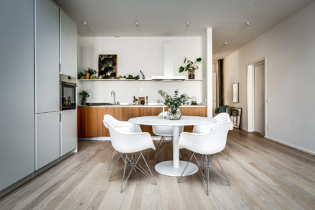 Airy, modern kitchen with white furniture, wooden accents, and potted plants.