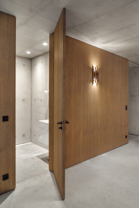 Minimalist hallway with wooden panels, recessed lighting, and a marble-tiled floor.