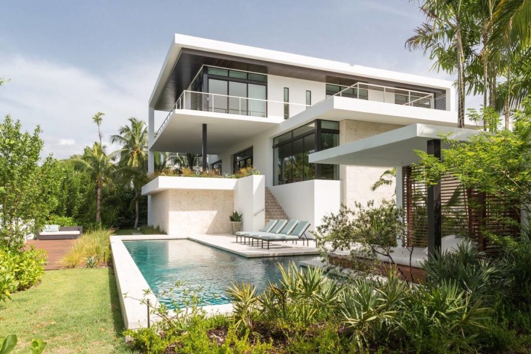 Sleek, modern villa with clean lines, expansive balconies, and a serene pool nestled in lush greenery.