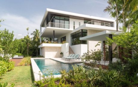 Sleek, modern villa with clean lines, expansive balconies, and a serene pool nestled in lush greenery.