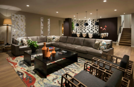 Modern, open-concept living space with plush sectional, patterned rug, and dark accent pieces.