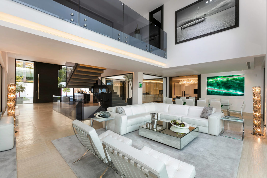 Impressive modern open-concept interior with high ceilings, glass walls, and sleek furniture.