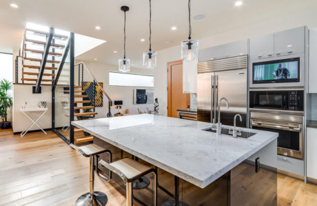 Stylish open-concept kitchen with modern appliances, marble countertop, and sleek pendant lights.