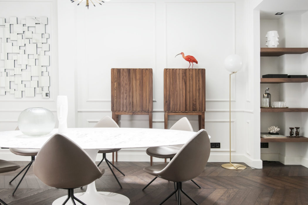 Modern, minimalist dining room with sleek furniture, wood floors, and a striking light fixture.