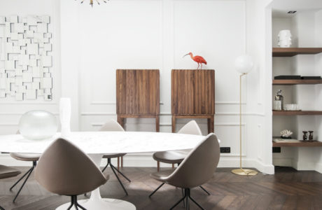 Modern, minimalist dining room with sleek furniture, wood floors, and a striking light fixture.