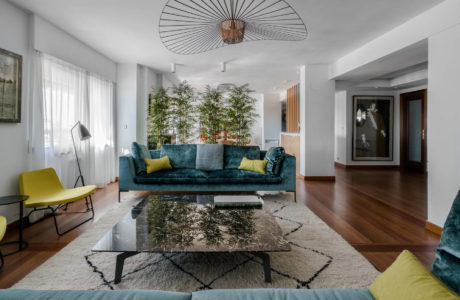 Spacious modern living room with plush teal sofa, glass coffee table, and statement lighting.