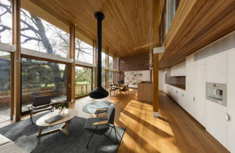Warm wood tones, open-concept layout, large windows framing the outdoor view.