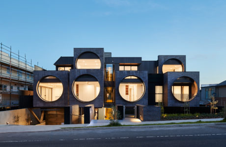 Striking modernist building with rhythmic circular apertures and warm interior lighting.