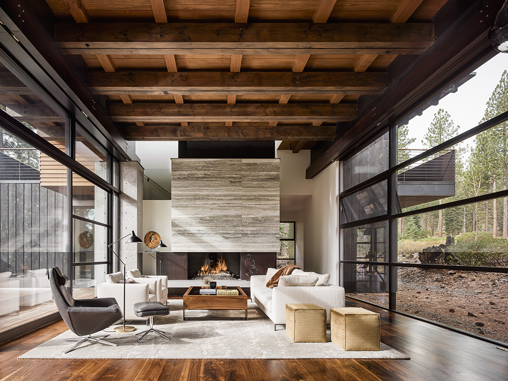 Rustic modern living room with wooden beams, fireplace, and expansive windows.