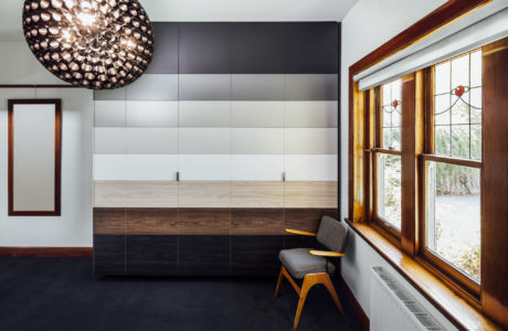 Modern room featuring tiled accent wall, wooden bench, and statement lighting fixture.