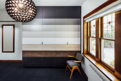 Modern room featuring tiled accent wall, wooden bench, and statement lighting fixture.