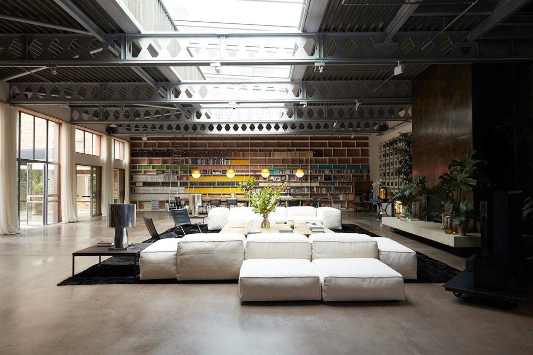 Spacious industrial-style living space with exposed brickwork, cozy sofas, and artistic lighting.