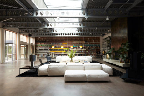 Spacious industrial-style living space with exposed brickwork, cozy sofas, and artistic lighting.