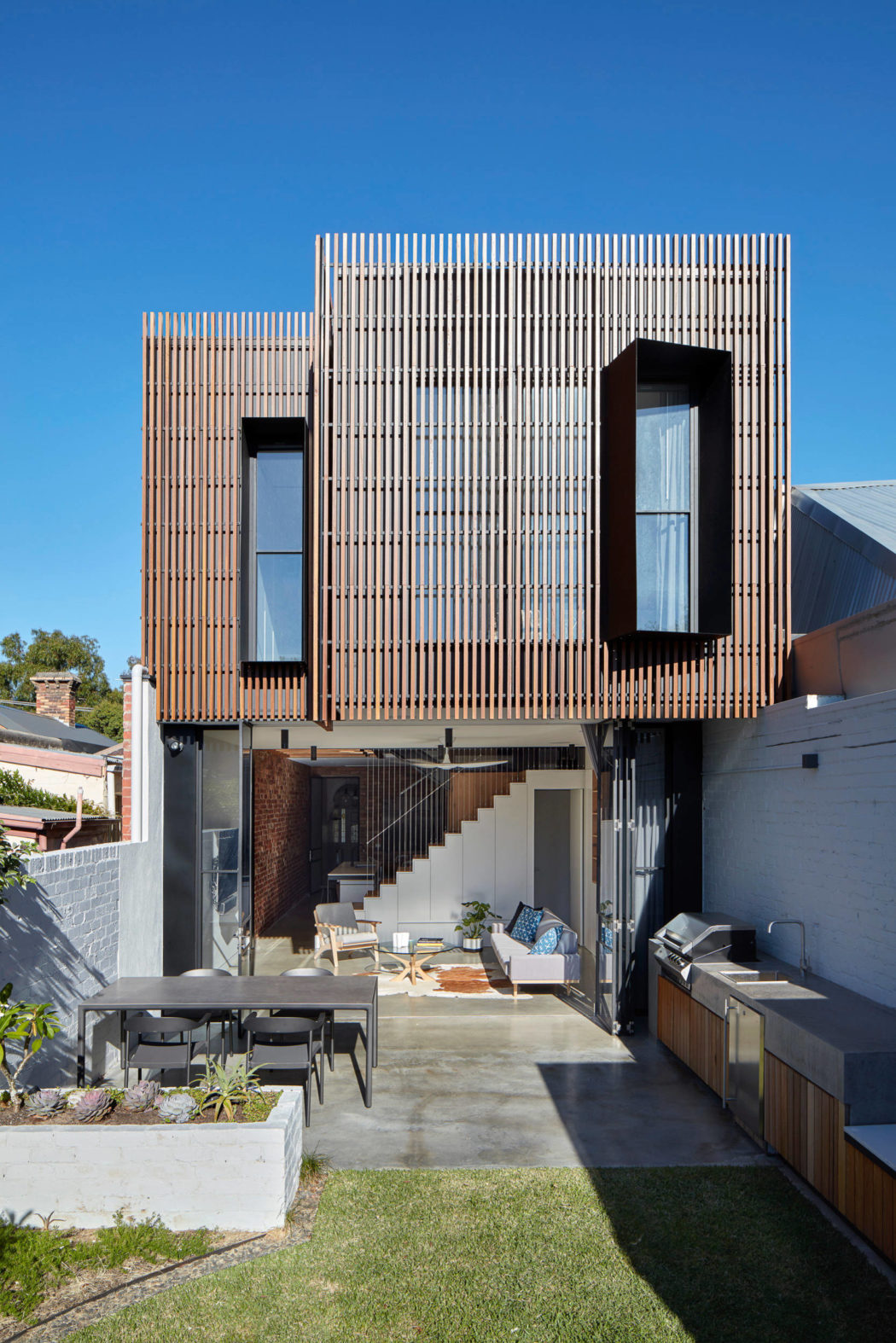 Modern two-story home with wooden slat facade and outdoor space.