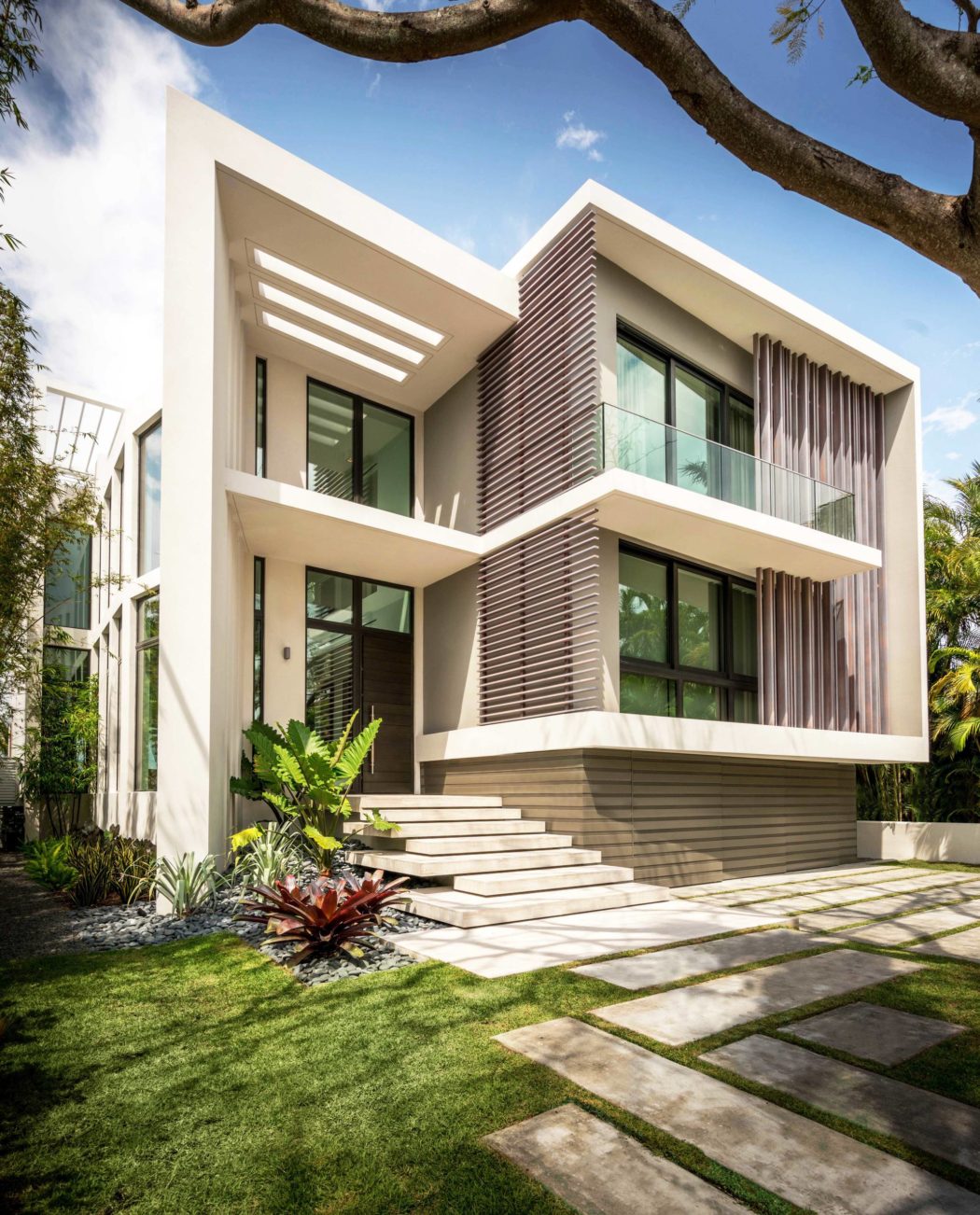 Modern, two-story tropical villa with clean lines, stone steps, and lush vegetation.