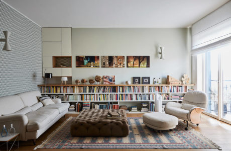 Spacious living room with extensive bookshelves, cozy seating, and vibrant floor rug.