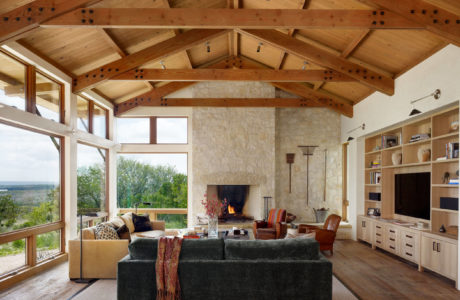 Spacious living room with exposed wooden beams, a fireplace, and large windows overlooking