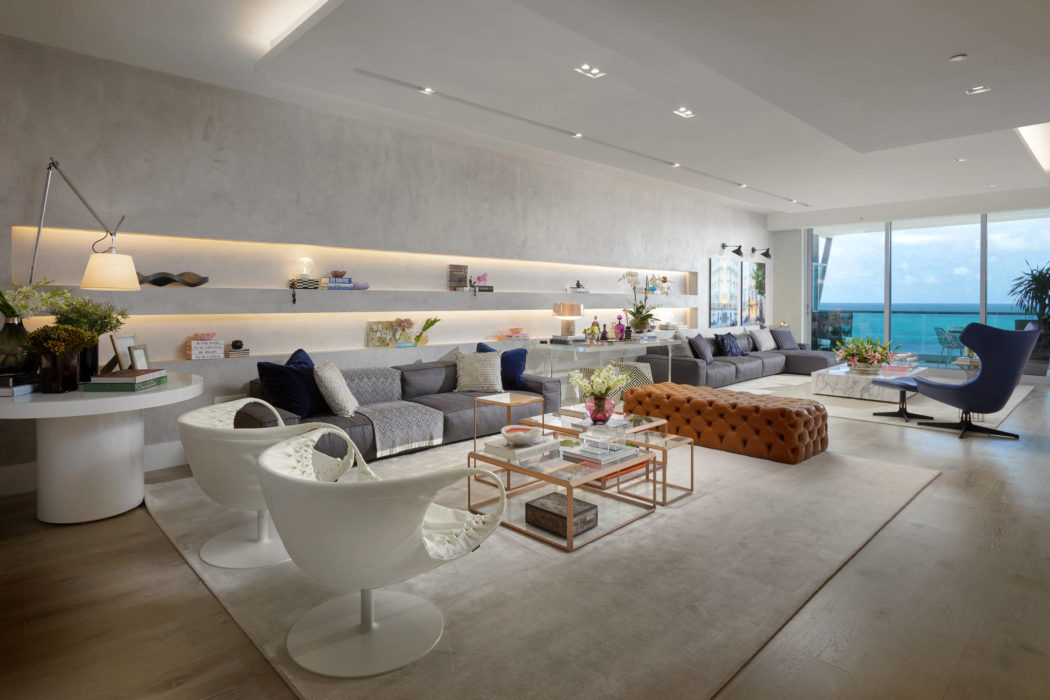Spacious living area with modern furniture, shelves, and panoramic ocean view.