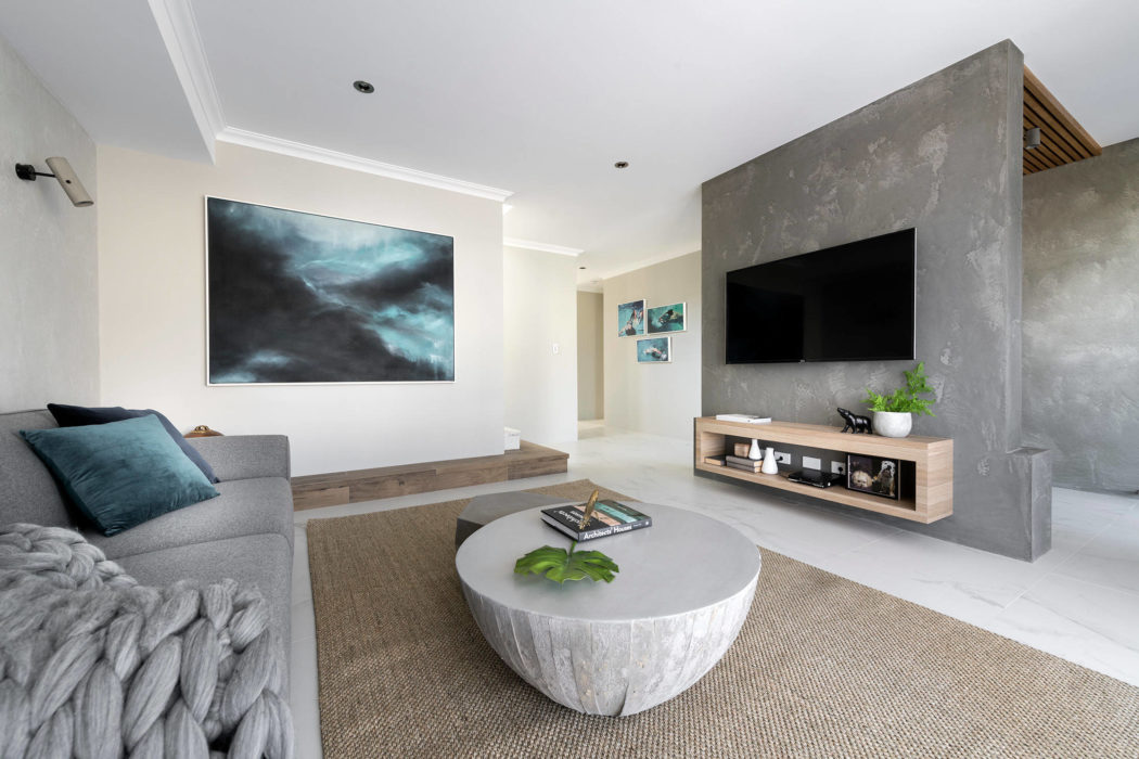 Sleek, modern living room with concrete accent wall, floating media console, and round concrete coffee table.