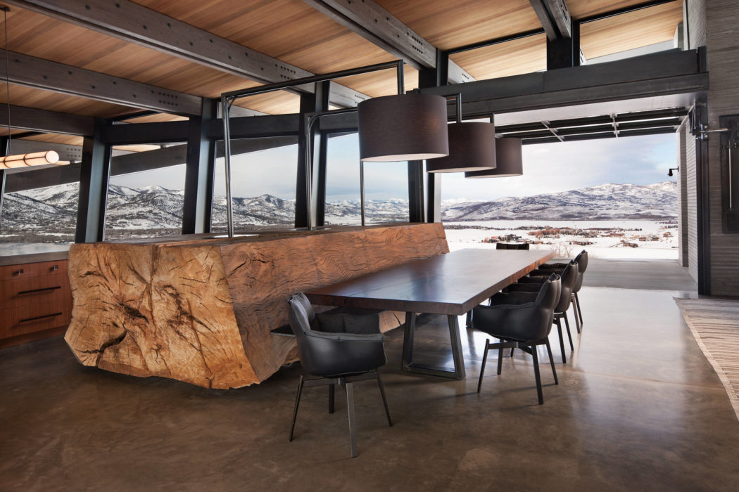Chic dining area with raw-wood bar and mountain view.