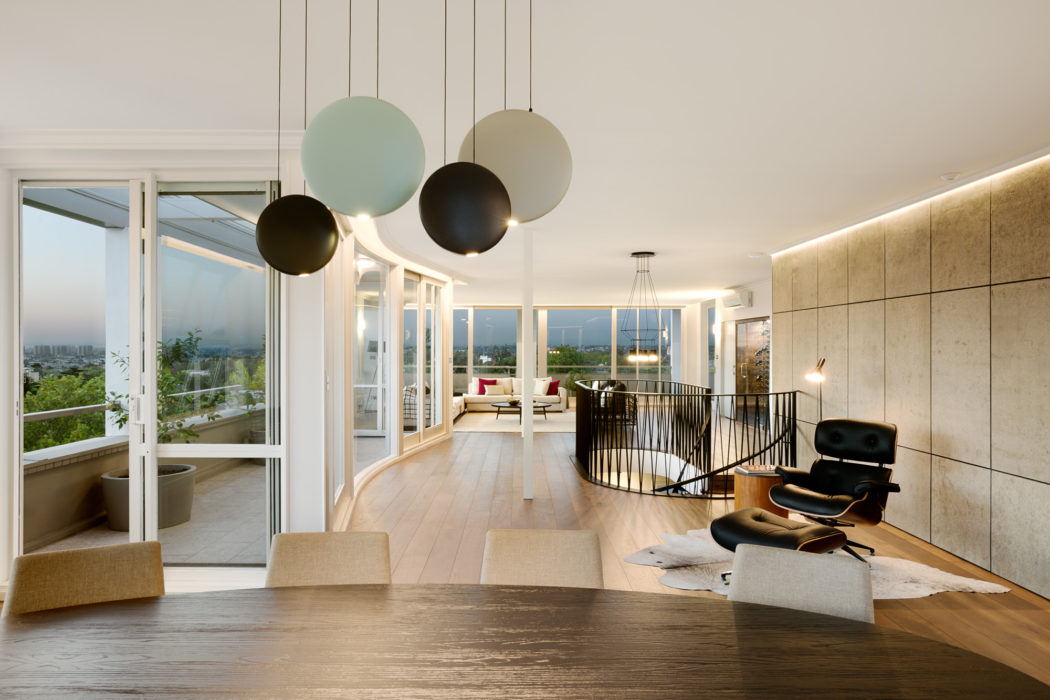 Modern open-concept living space with floor-to-ceiling windows, pendant lighting, and wooden floors.
