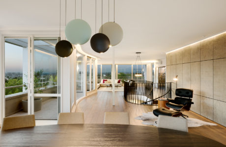 Modern open-concept living space with floor-to-ceiling windows, pendant lighting, and wooden floors.