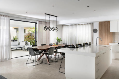 Modern kitchen with island and dining area with geometric pendant lights.