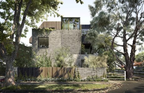 A modern, multi-story building featuring a unique brick facade, surrounded by lush greenery.