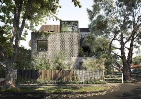 A modern, multi-story building featuring a unique brick facade, surrounded by lush greenery.