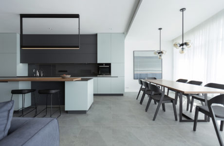 Sleek, minimalist kitchen and dining area with dark cabinetry, neutral tones, and modern lighting.