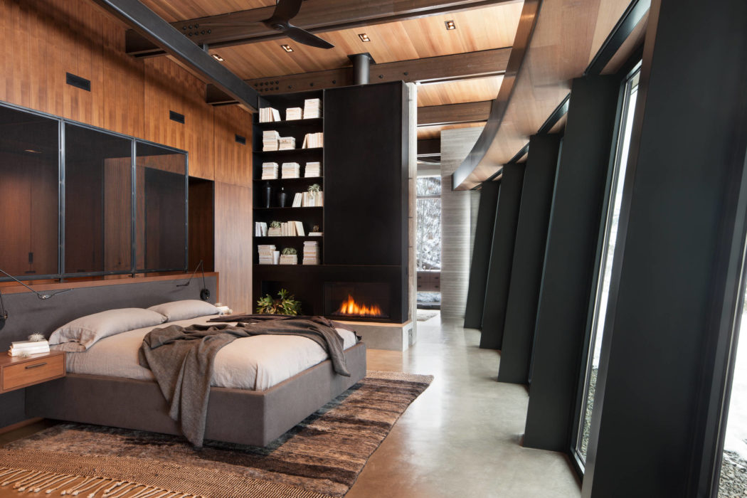 Modern bedroom with a fireplace, wood paneling, and floor-to-ceiling windows