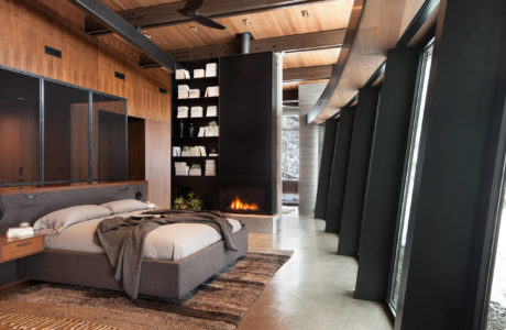 Modern bedroom with a fireplace, wood paneling, and floor-to-ceiling windows