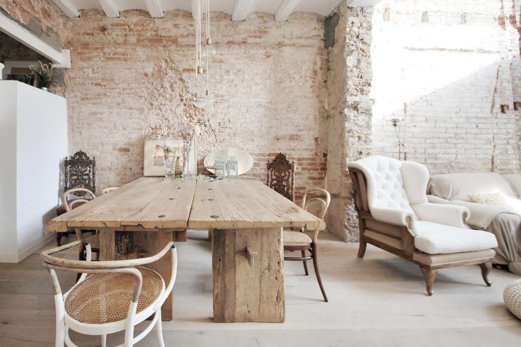 Rustic dining room with exposed brick walls, wooden table, and antique furnishings.