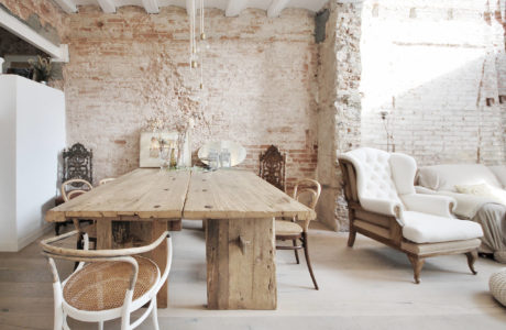 Rustic dining room with exposed brick walls, wooden table, and antique furnishings.